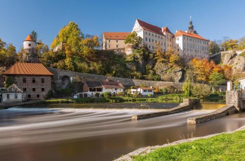 a river in a town with buildings on a mountain at Hotel Panská in Bechyně