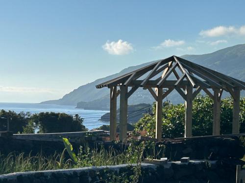 a wooden gazebo with a view of the water at Cá Por Casa Pico-Faia in Prainha de Baixo