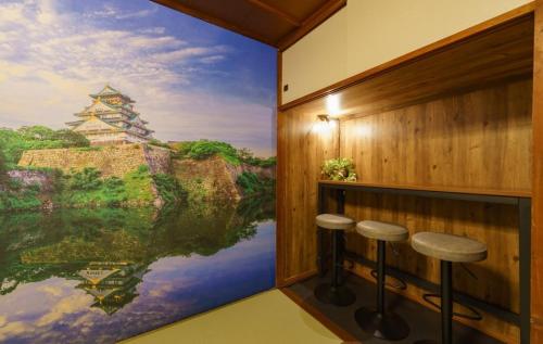 a room with a large painting on the wall with stools at SAMURAI Base in Hakone