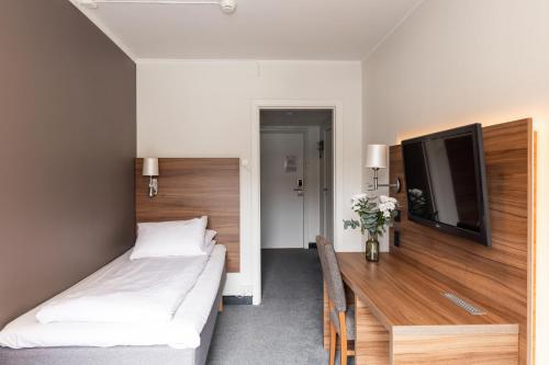 a bedroom with two beds and a flat screen tv at Thon Partner Hotel Backlund in Levanger