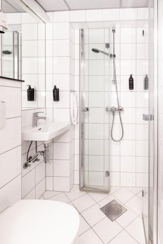 a white bathroom with a shower and a sink at Thon Partner Hotel Backlund in Levanger