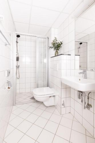a white bathroom with a toilet and a sink at Thon Partner Hotel Backlund in Levanger