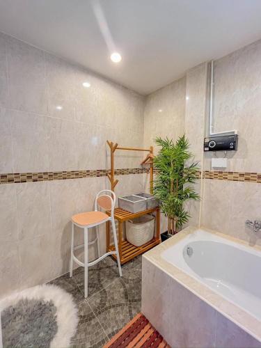 a bathroom with a tub and a table and a stool at VS Resortวีเอส รีสอร์ท ท่าศาลา in Ban Thang Khun
