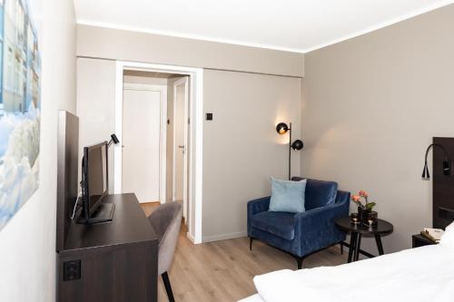 a room with a bed and a blue chair and a television at Thon Partner Hotel Backlund in Levanger