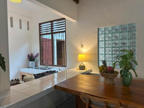 a kitchen with a wooden table and a large window at Omah Padang Homestay Yogyakarta in Timuran