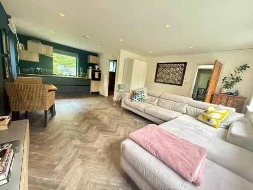 a large living room with a couch and a kitchen at Studio with kitchen nestled lovely wooded cul du sac in New Malden
