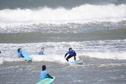 a group of surfers riding a wave in the ocean at Santacruz Surf Camp Morocco in Tamraght Ouzdar