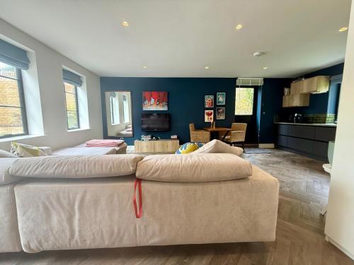 a living room with a couch and a kitchen at Studio with kitchen nestled lovely wooded cul du sac in New Malden