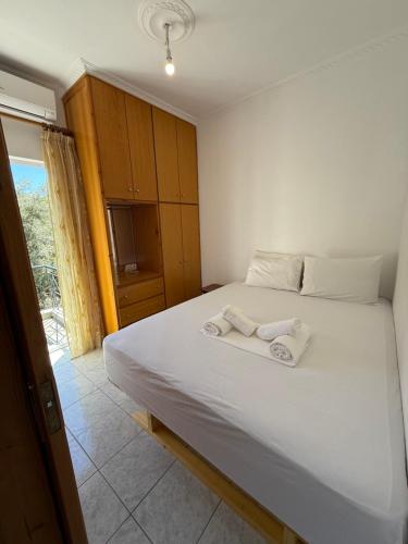 a bedroom with a white bed with two towels on it at βίλα Ολγα in Kolónion