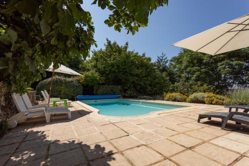 une piscine avec deux chaises et un parasol dans l'établissement Maison Grise, à Saint-André-dʼAllas