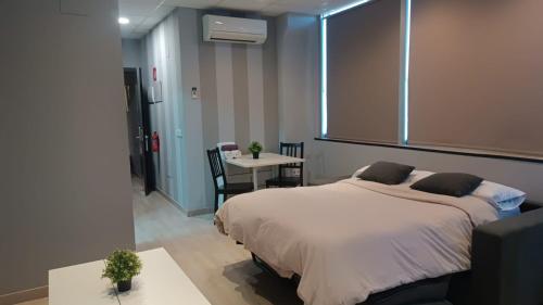 a bedroom with a large bed and a table at Estudios 85 - Cerca de Madrid, Toledo y Parque Warner in Parla