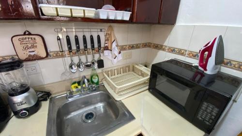 a kitchen counter with a sink and a microwave at Pool view first floor 2 Bdrm Condo in Punta Cana