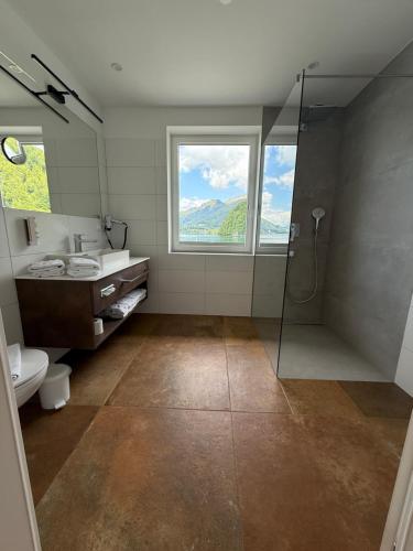 a bathroom with a shower and a sink and a window at Seehotel Lilly in Strobl