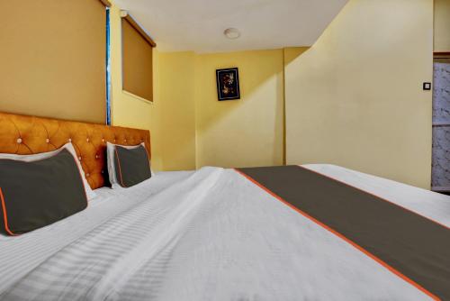 a bedroom with a large white bed with an orange headboard at Super Hotel O Golden Suites in Turambhe