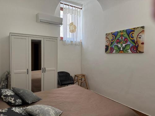 a bedroom with a bed and a painting on the wall at Casa Mimí in Cefalù