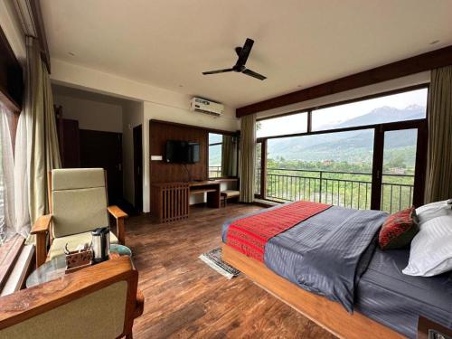 a bedroom with a bed and a large window at Crimson inn by Senderos De Pine in Manāli