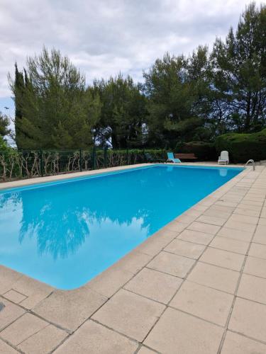 une piscine bleue avec des arbres en arrière-plan dans l'établissement Appartement vu mer et montagnes, à Villeneuve-Loubet