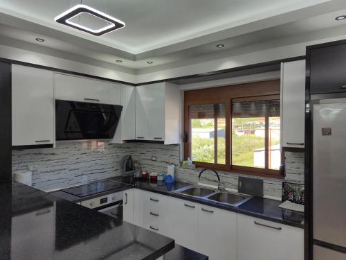 a kitchen with white cabinets and a sink and a window at Villa Ari in Berat