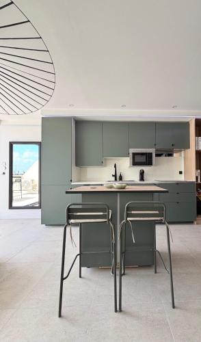 une cuisine avec des armoires vertes et une table avec deux chaises dans l'établissement Duchesse Luxe Cap - Naturiste, au Cap d'Agde