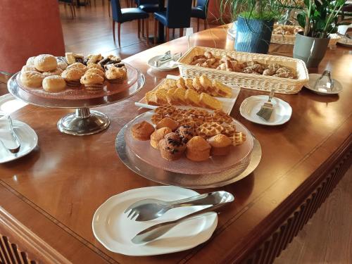 a table with several plates of pastries and silver servers at Hotel Villa Maria in Desenzano del Garda
