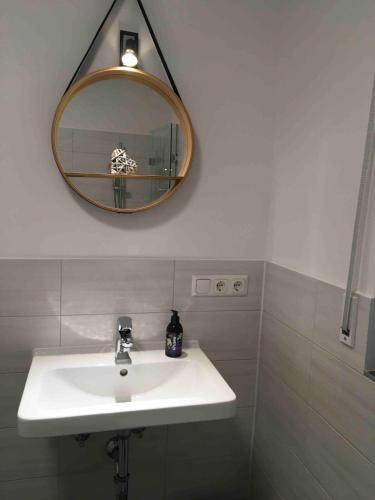 a bathroom with a white sink and a mirror at Großzügige individuelle Wohnung am Starnberger See in Münsing am Starnberger See