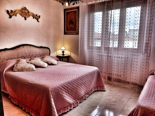 a bedroom with a bed with a pink blanket and windows at Grande Appartamento in Villa con 2 camere, terrazze, giardino, barbecue e posto auto privato Tutti spazi uso esclusivo in Cecina