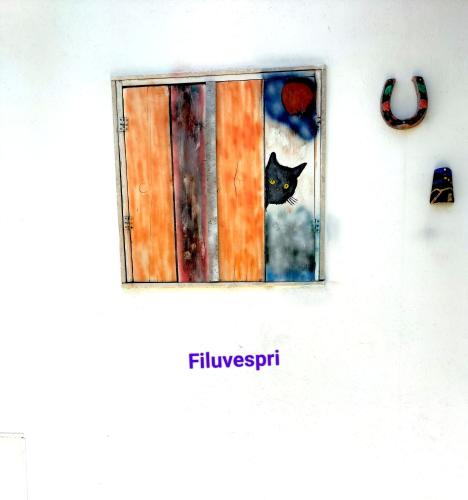 a black cat is looking out of a window at Filuvespri in Comiso