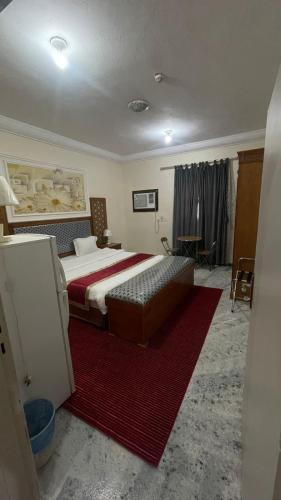 a bedroom with a large bed and a red rug at شقق الخيول البرونزية للشقق المخدومة in Şabyā