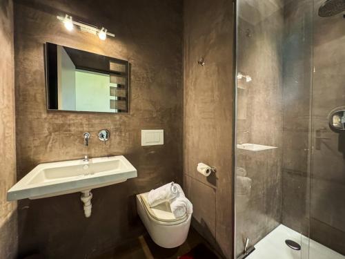 a bathroom with a sink and a toilet and a shower at Modernes Bergblick Apartment im Herzen von Andermatt Sonne & Terasse in Andermatt