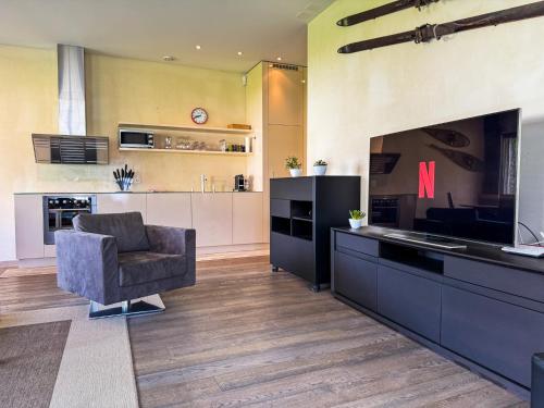 a living room with a chair and a kitchen at Modernes Bergblick Apartment im Herzen von Andermatt Sonne & Terasse in Andermatt