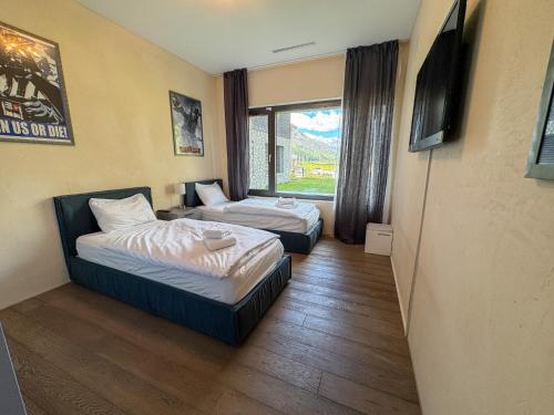 a hotel room with two beds and a window at Modernes Bergblick Apartment im Herzen von Andermatt Sonne & Terasse in Andermatt