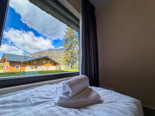 a bed with a towel on it next to a window at Modernes Bergblick Apartment im Herzen von Andermatt Sonne & Terasse in Andermatt