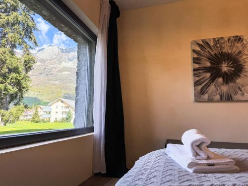 a bedroom with a window with a towel on a bed at Modernes Bergblick Apartment im Herzen von Andermatt Sonne & Terasse in Andermatt