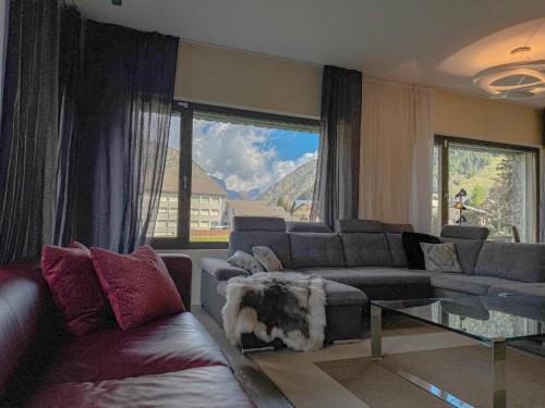 a living room with couches and a large window at Modernes Bergblick Apartment im Herzen von Andermatt Sonne & Terasse in Andermatt