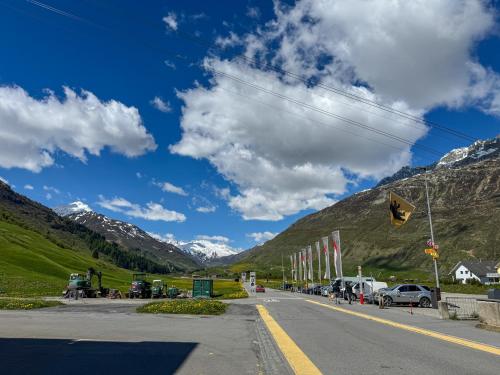 a road with mountains in the background and a blue at Modernes Bergblick Apartment im Herzen von Andermatt Sonne & Terasse in Andermatt