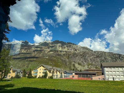 a mountain in the distance with houses and a mountain at Modernes Bergblick Apartment im Herzen von Andermatt Sonne & Terasse in Andermatt