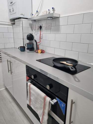 a kitchen with a stove with a frying pan on it at Wembley Stadium and OVO Arena Apartment in London