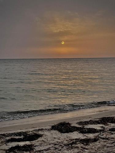 a sunset over the ocean with the moon in the sky at Tokyo in Akouda