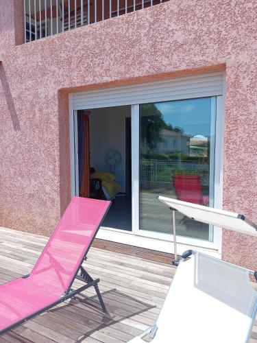 une chaise pliante rose et une table sur une terrasse dans l'établissement Haute-Corse Bas de villa , 2 chambres de 70 m2 , vue mer , jardin et terrasse, à Furiani