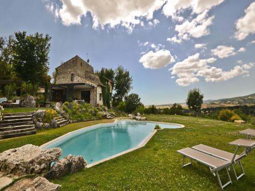 a swimming pool in front of a stone house at Agriturismo Fontenuova in Saturnia