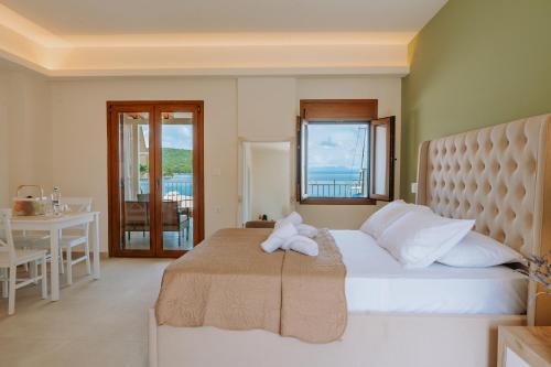 a bedroom with a large white bed with a table and a balcony at Sivota Seafront Studios in Sivota