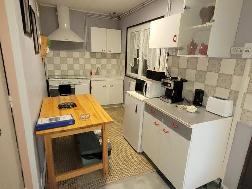 Elle comprend une petite cuisine avec des placards blancs et une table en bois. dans l'établissement Chalet 