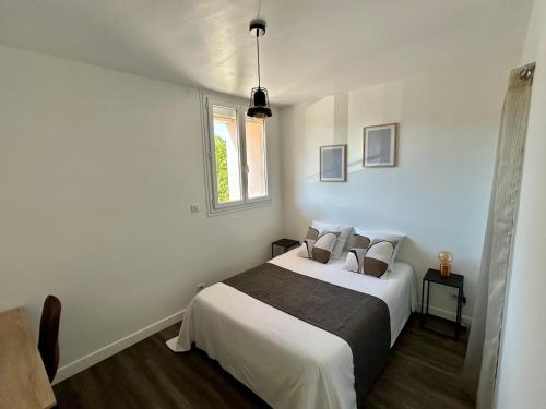 une chambre avec un lit avec des draps blancs et une fenêtre dans l'établissement Charmant T3 proche centre ville, à Quimper