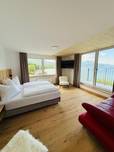 a bedroom with a large bed and large windows at Seehotel Lilly in Strobl