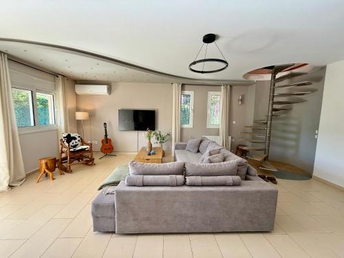 a living room with a gray couch and a television at Nea Makri Holiday Villa in Nea Makri