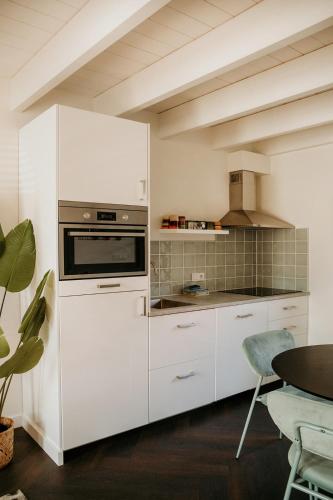 a kitchen with white cabinets and a stove at Slapen aan Zee in Vlissingen