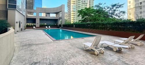 a swimming pool with two lounge chairs and a swimming pool at Charming Modern Condo in BGC in Manila