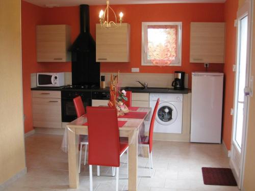 une cuisine avec une table à manger et des chaises rouges dans l'établissement Les Pieux -6km de la mer, à Grosville