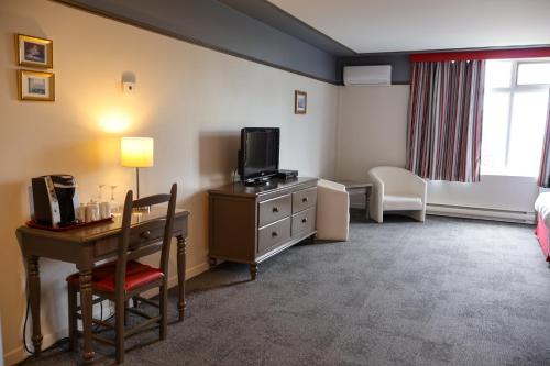 a hotel room with a desk and a tv at Hôtel au Petit Berger in La Malbaie