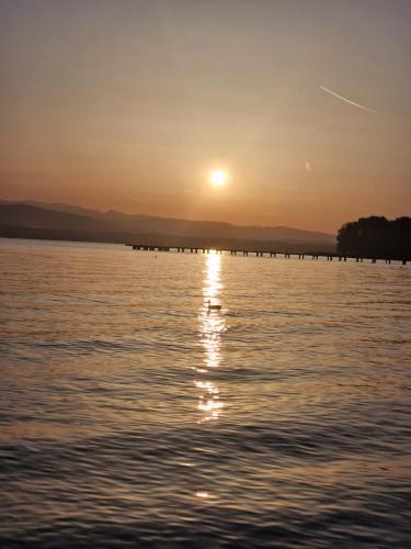 a sunset over a body of water with a pier at SirmioneRooms in Sirmione